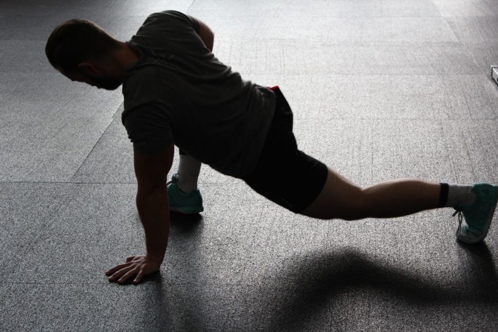 An athlete doing a warm-up mobility stretch on the gym floor before training