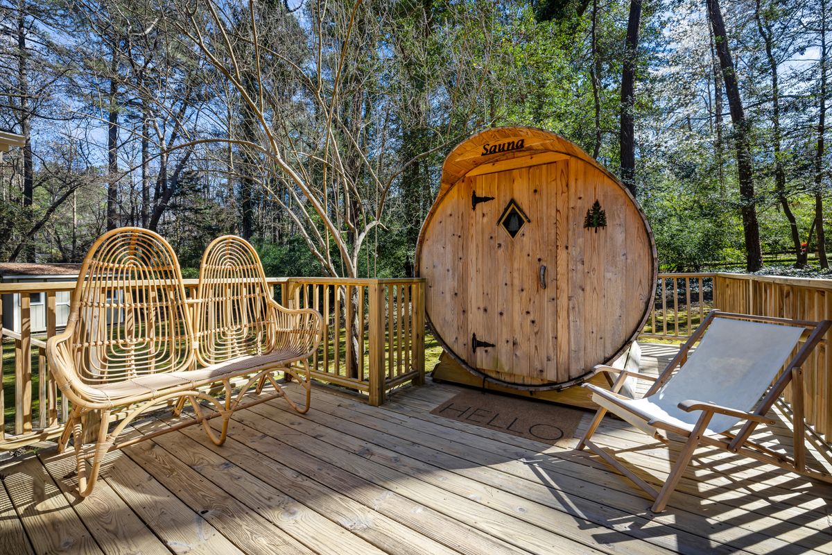 An outdoor wooden barrel sauna on a deck.