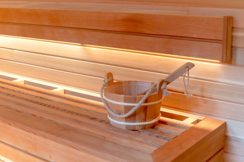Warm traditional wooden sauna interior with a bucket and ladle