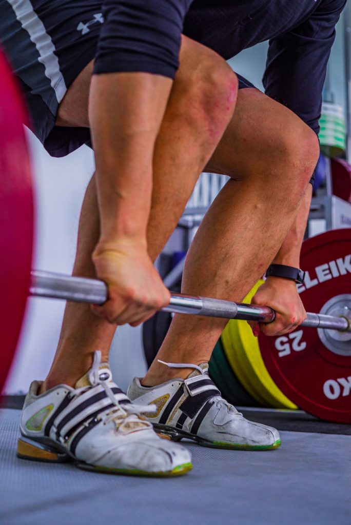 Hands gripping a loaded barbell tightly to create full-body tension