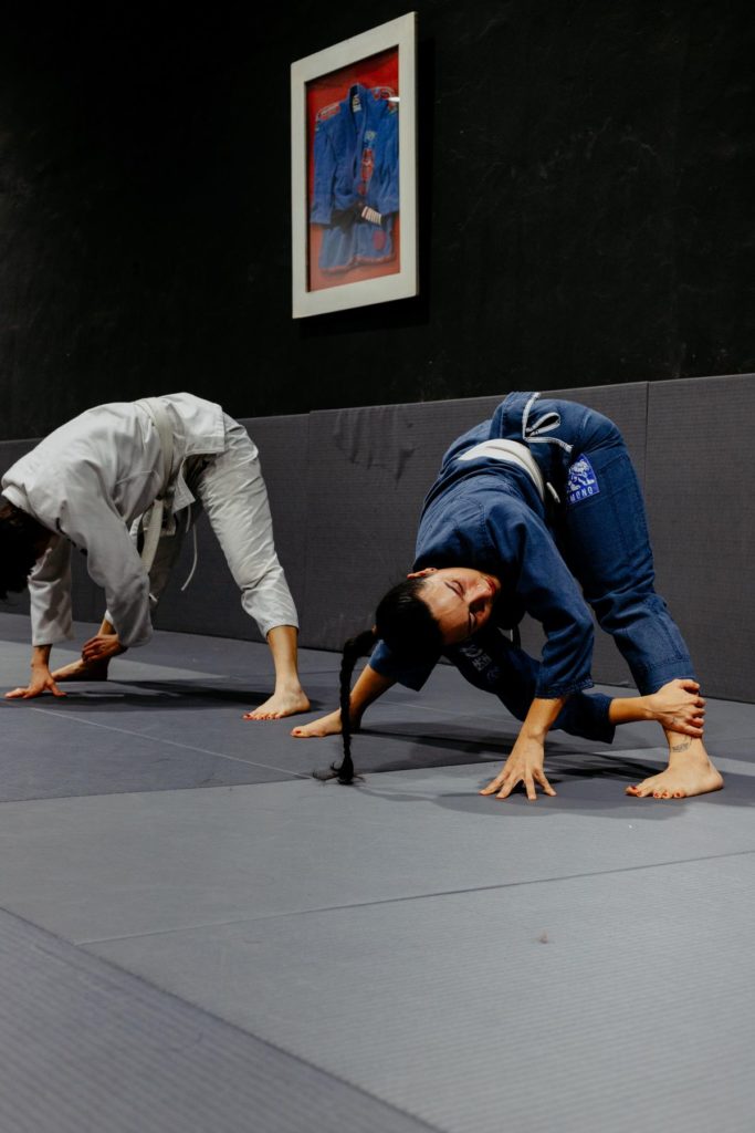Two grapplers practicing a throw and a safe breakfall on the mat