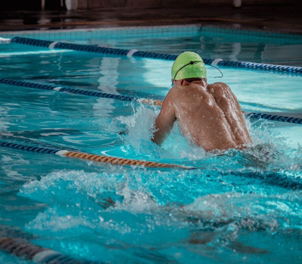 A swimmer drilling freestyle body position in a pool lane to cut drag and swim faster