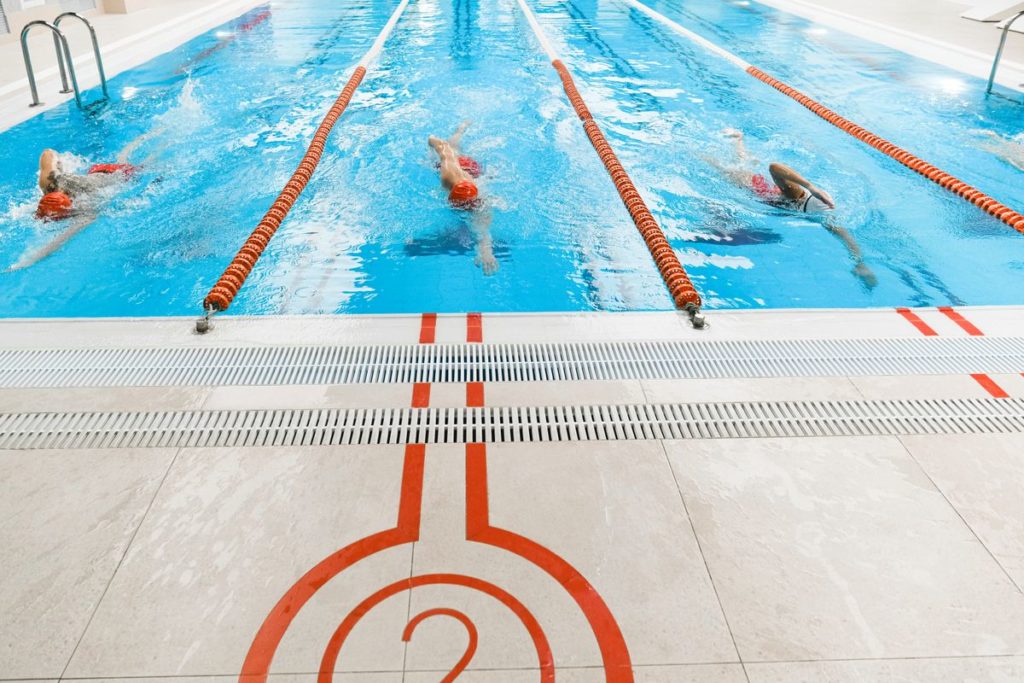 Swimmers doing lap sets in a clear blue lane pool